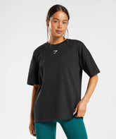 امرأة ترتدي تي شيرت Fraction كبير الحجم من Gymshark | تم التأكيد على United We Sweat من خلال الراحة والأناقة التي توفرها طماقها الخضراء.
